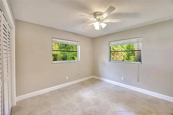 Unfurnished room featuring light tile patterned flooring, a ceiling fan, and baseboards
