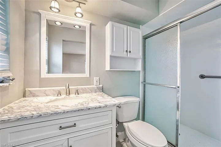 Full bath with toilet, an enclosed shower, and vanity