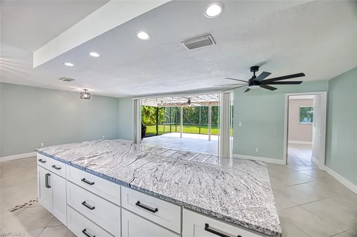 Kitchen featuring visible vents, light tile patterned floors, a ceiling fan, and light stone countertops