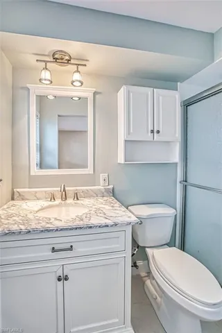 Full bath with toilet, tile patterned flooring, an enclosed shower, and vanity
