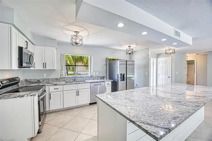Kitchen with light tile patterned floors, recessed lighting, white cabinets, and appliances with stainless steel finishes