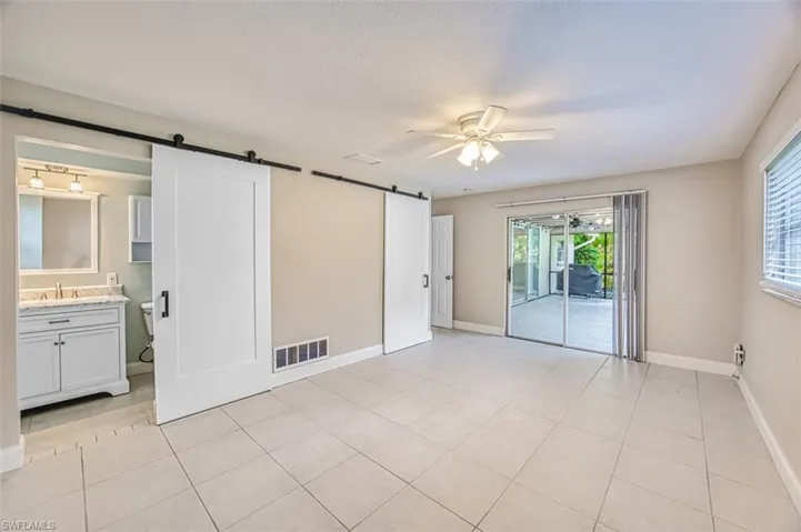 Unfurnished bedroom featuring visible vents, access to outside, a barn door, and baseboards