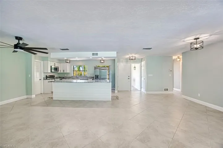 Unfurnished living room featuring light tile patterned floors, a textured ceiling, visible vents, and baseboards