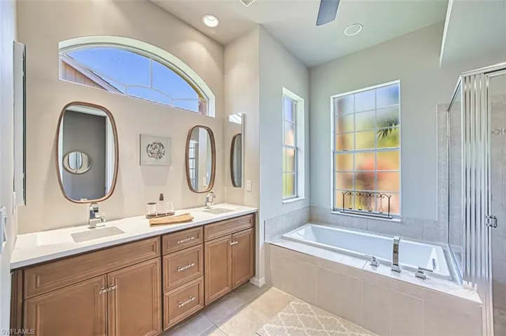 Full bath featuring double vanity, a sink, a garden tub, and tile patterned flooring