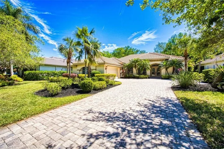 View of front facade featuring decorative driveway, an attached garage, a tile roof, stucco siding, and french doors