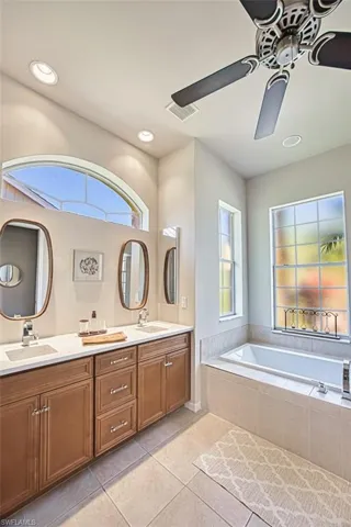 Full bathroom with double vanity, ceiling fan, a sink, and tile patterned floors
