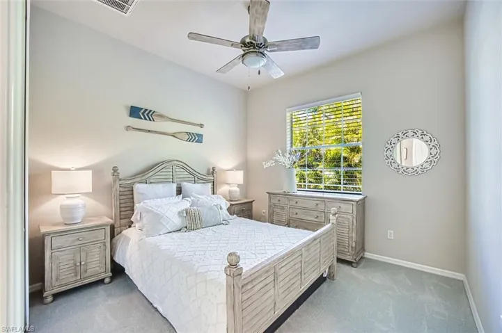Bedroom featuring baseboards, visible vents, a ceiling fan, and light carpet