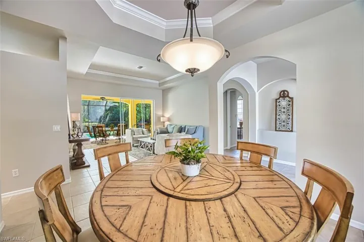 Dining area featuring baseboards, light tile patterned floors, ornamental molding, and a raised ceiling
