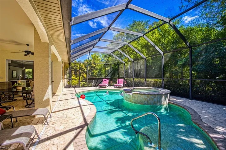 View of swimming pool featuring glass enclosure, a pool with connected hot tub, ceiling fan, and a patio area