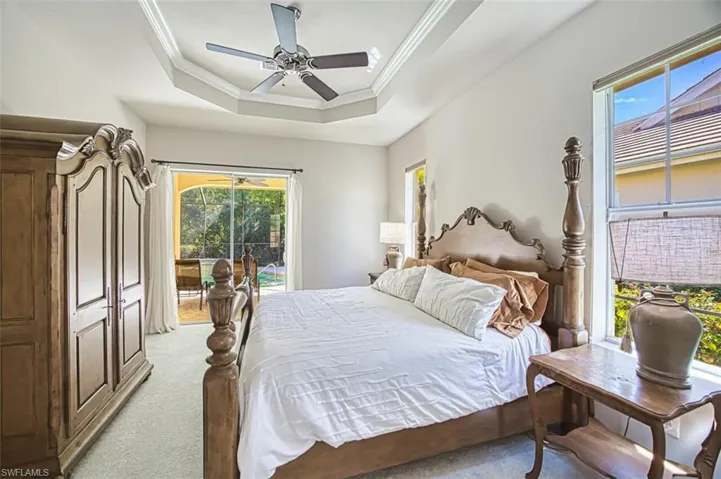 Bedroom with light carpet, a tray ceiling, access to exterior, and crown molding
