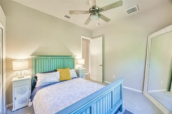 Bedroom with light carpet, baseboards, visible vents, and ceiling fan