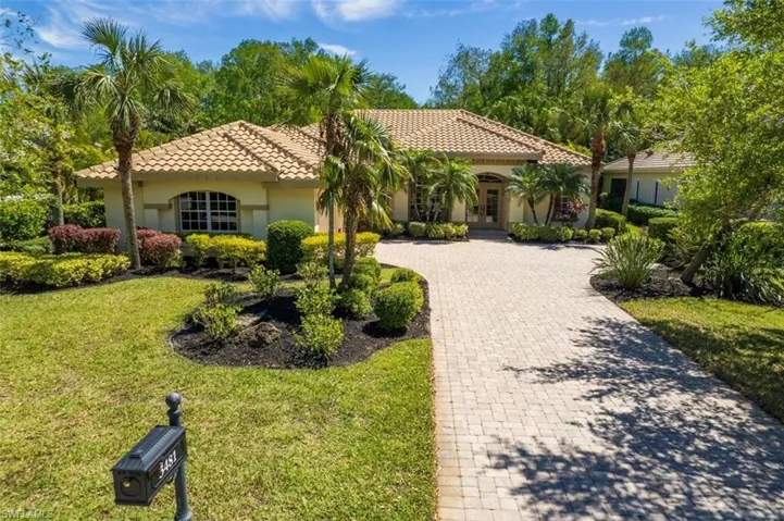 Mediterranean / spanish-style house with stucco siding, a front yard, a tile roof, driveway, and french doors