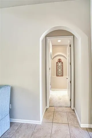 Hallway with baseboards, arched walkways, and light tile patterned floors