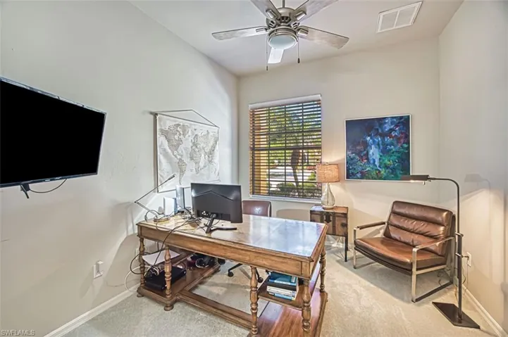 Office with baseboards, visible vents, carpet, and a ceiling fan