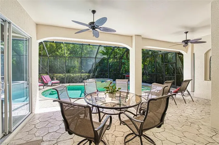 View of patio with an in ground hot tub, a lanai, an outdoor pool, and a ceiling fan