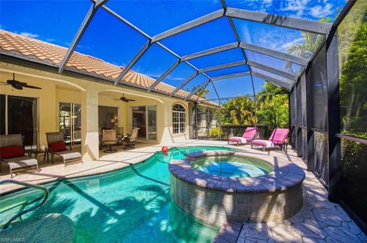 View of swimming pool featuring a patio, ceiling fan, a pool with connected hot tub, and a lanai