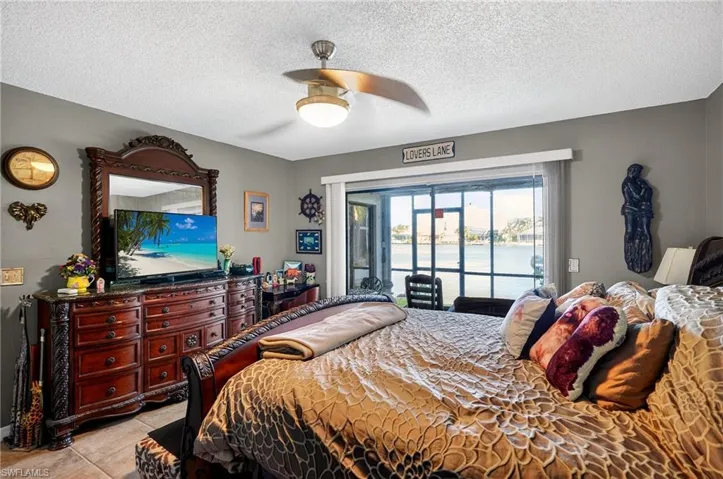 Bedroom featuring access to outside, a textured ceiling, ceiling fan, and light tile patterned floors
