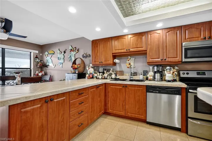 Kitchen featuring wood finish cabinets, stainless steel appliances, an ornate ceiling, light countertops, and recessed lighting