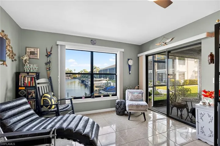 Living area featuring a water view, light tile patterned flooring, and ceiling fan