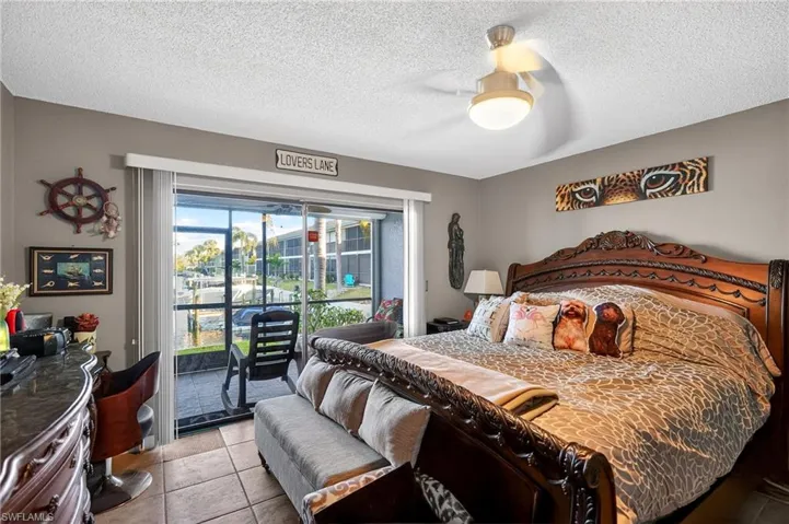 Bedroom featuring access to outside, light tile patterned floors, a ceiling fan, and a textured ceiling