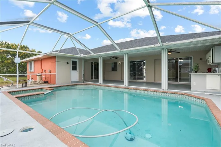 View of pool with an in ground hot tub, a patio, ceiling fan, and glass enclosure