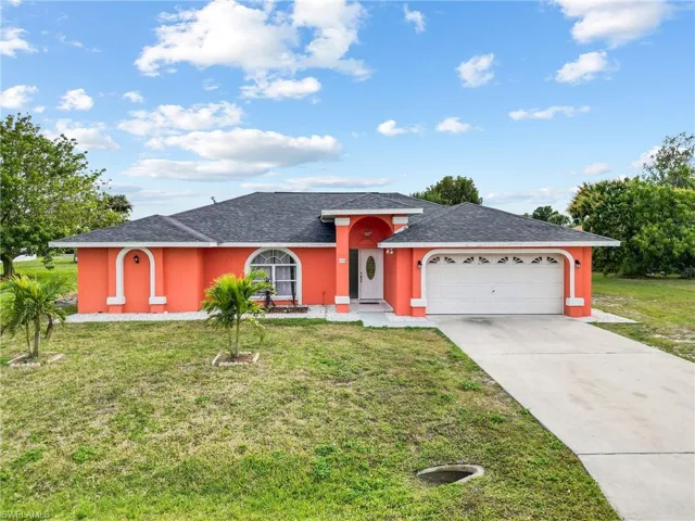 Single story home with a garage and a front lawn