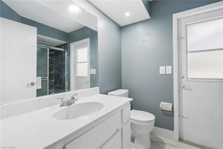 Bathroom with vanity, toilet, and a shower with shower door