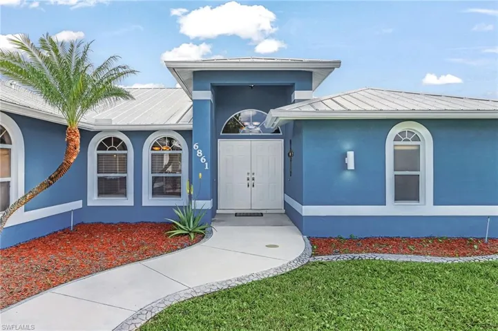 Doorway to property with a standing seam roof, stucco siding, and a yard
