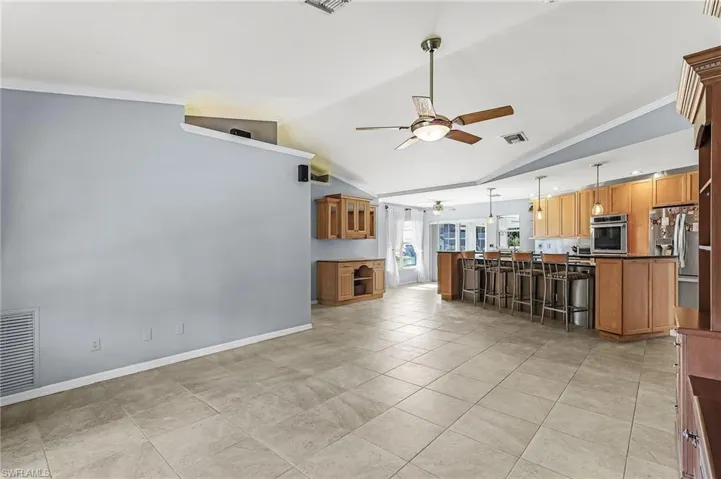 Kitchen featuring wood finish cabinets, a kitchen bar, ceiling fan, pendant lighting, and ornamental molding