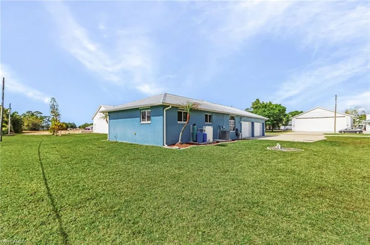 Rear view of property with a yard, a garage, stucco siding, and concrete driveway