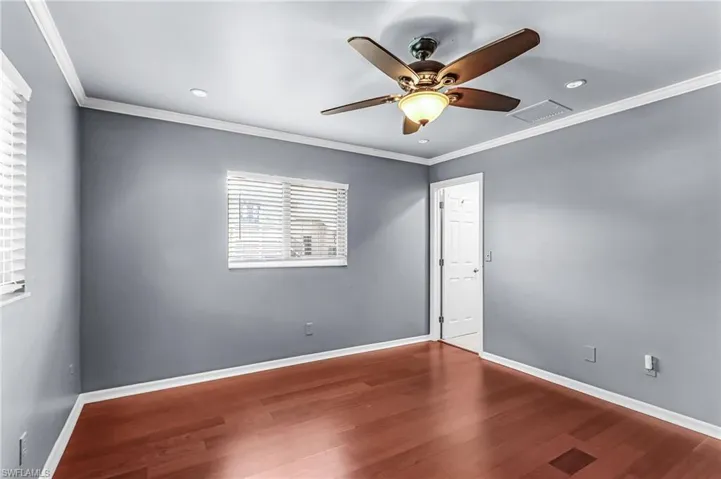 Spare room with crown molding, a ceiling fan, dark wood-type flooring, and recessed lighting