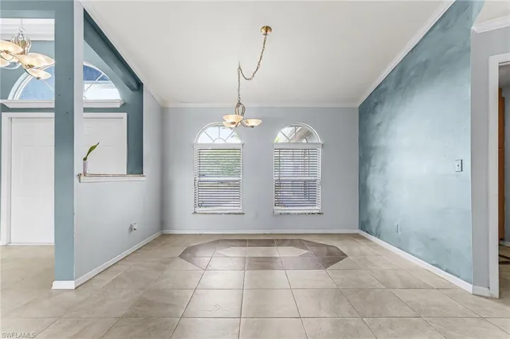 Unfurnished dining area featuring hanging lights, crown molding, and light tile patterned flooring