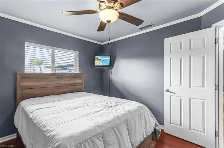 Bedroom featuring crown molding, dark wood-type flooring, and ceiling fan
