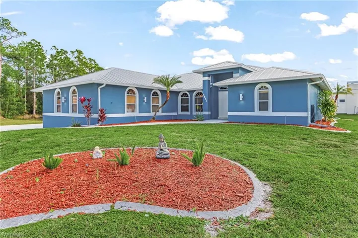 View of front of home with stucco siding, a front lawn, and a metal roof