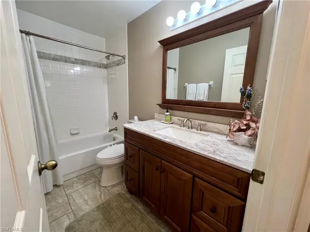 Full bathroom featuring shower / bathtub combination with curtain, vanity, tile patterned floors, and toilet