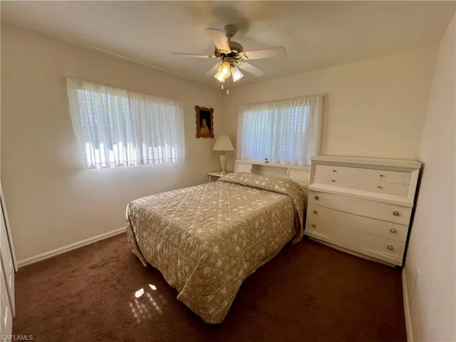 Carpeted bedroom featuring ceiling fan and multiple windows