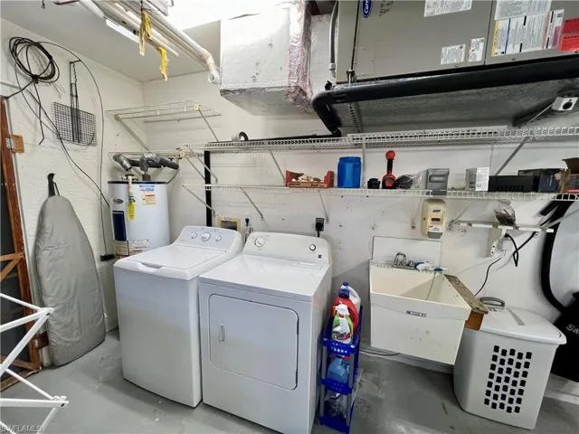 Clothes washing area featuring water heater, separate washer and dryer, and sink