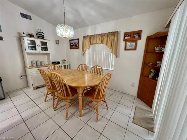 Tiled dining area featuring a chandelier and lofted ceiling