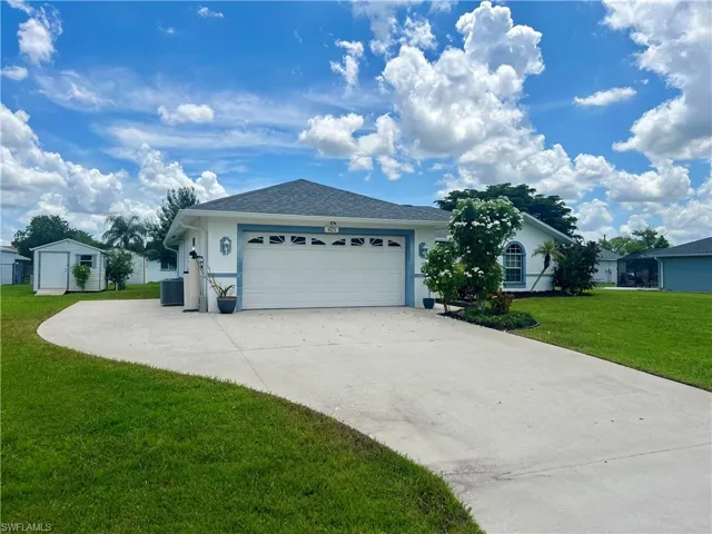 Ranch-style home featuring an outdoor structure, a front lawn, central AC, and a garage