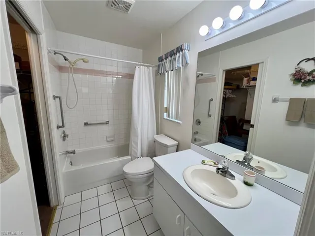 Full bathroom with shower / bath combo, tile patterned floors, vanity, and toilet