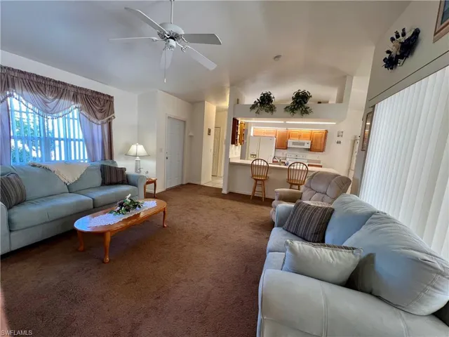Carpeted living room with ceiling fan and lofted ceiling