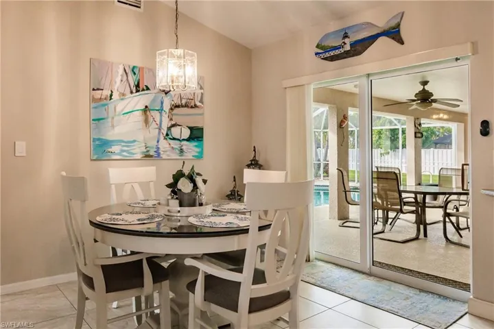 Dining area featuring light tile patterned floors and ceiling fan with notable chandelier