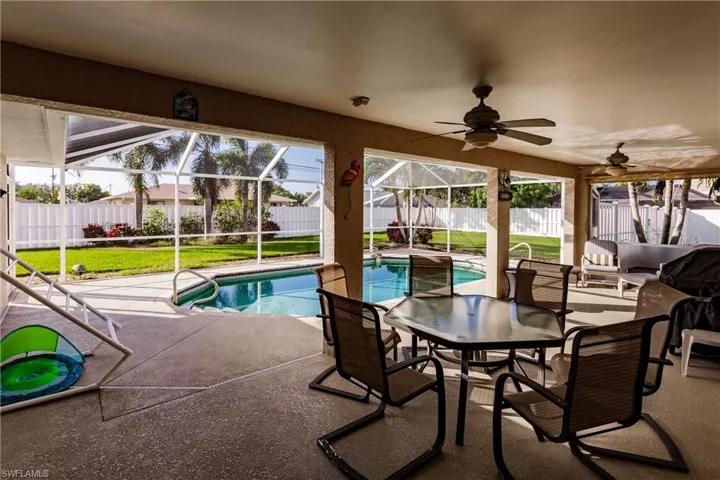 View of swimming pool with a yard, a patio, glass enclosure, and ceiling fan