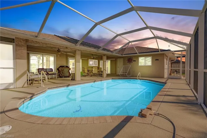 Pool at dusk with a lanai, a patio area, and ceiling fan