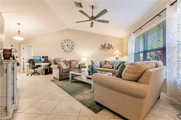 Living room featuring ceiling fan, light tile patterned floors, and lofted ceiling