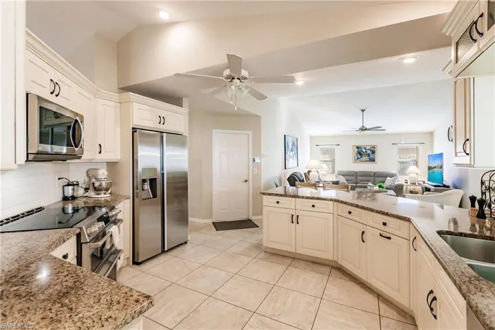 Kitchen featuring stainless steel appliances, vaulted ceiling, tasteful backsplash, and light stone counters