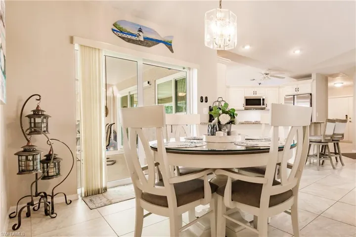 Dining space with ceiling fan with notable chandelier and light tile patterned flooring