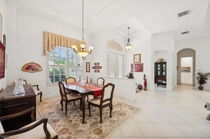 Dining space featuring arched walkways, a chandelier, light tile patterned floors, and crown molding