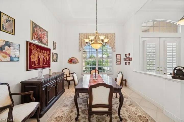 Dining space featuring a chandelier, plenty of natural light, light tile patterned floors, a tray ceiling, and crown molding