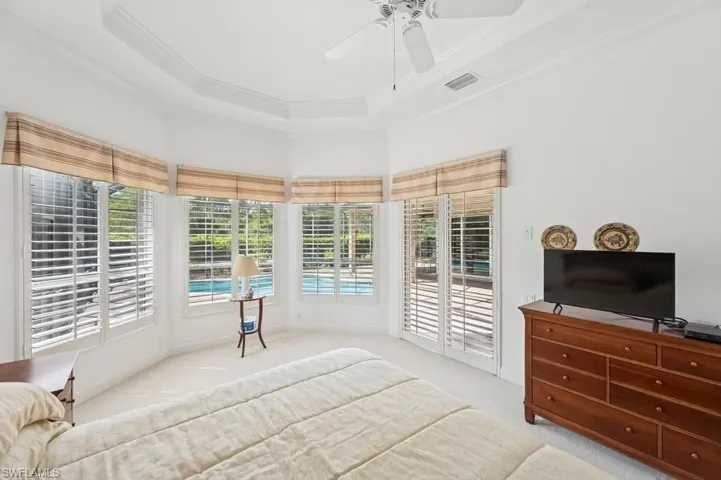 Carpeted bedroom featuring access to exterior, crown molding, a ceiling fan, and a tray ceiling